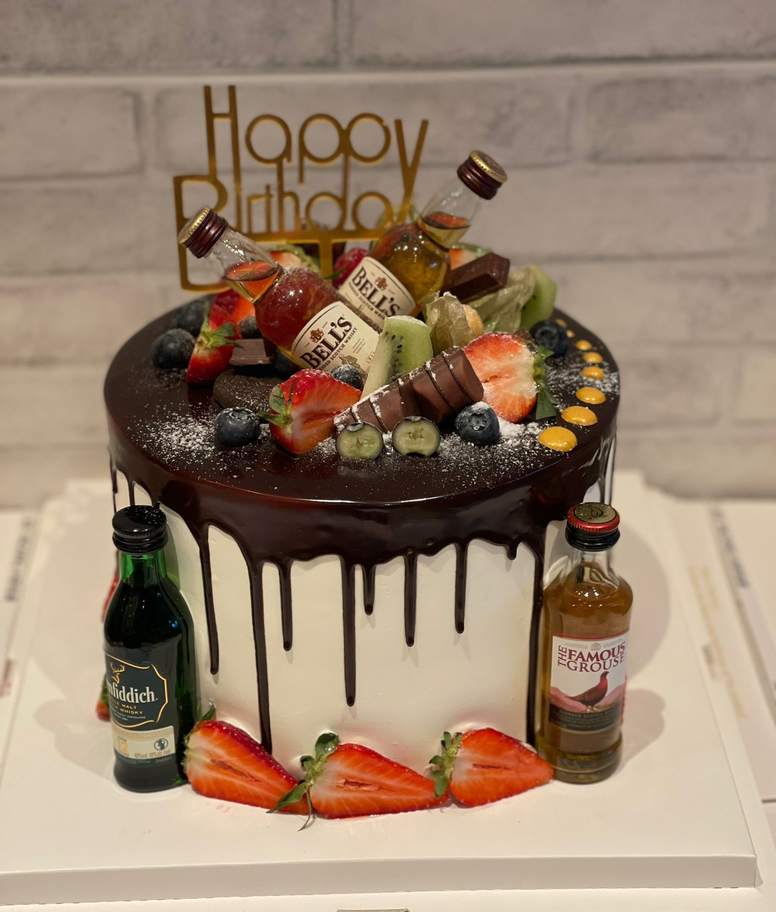 Chocolate drip cake dressed with miniature bottles and treats, La-Luscious Bakery Grays