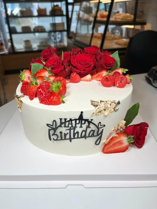 Ivory celebration cake with fresh red roses, strawberries and gold leaf