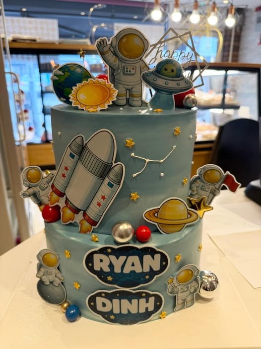Two-tier children's space birthday cake with astronauts, rockets and planets