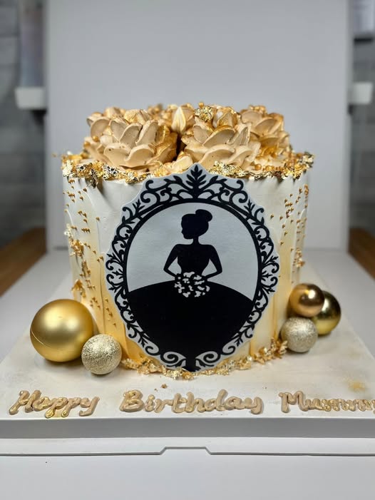 Elegant black and gold birthday cake with piped gold blooms and a silhouette cameo