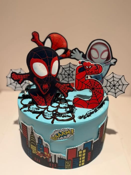 Children's superhero birthday cake with comic city skyline and web detailing
